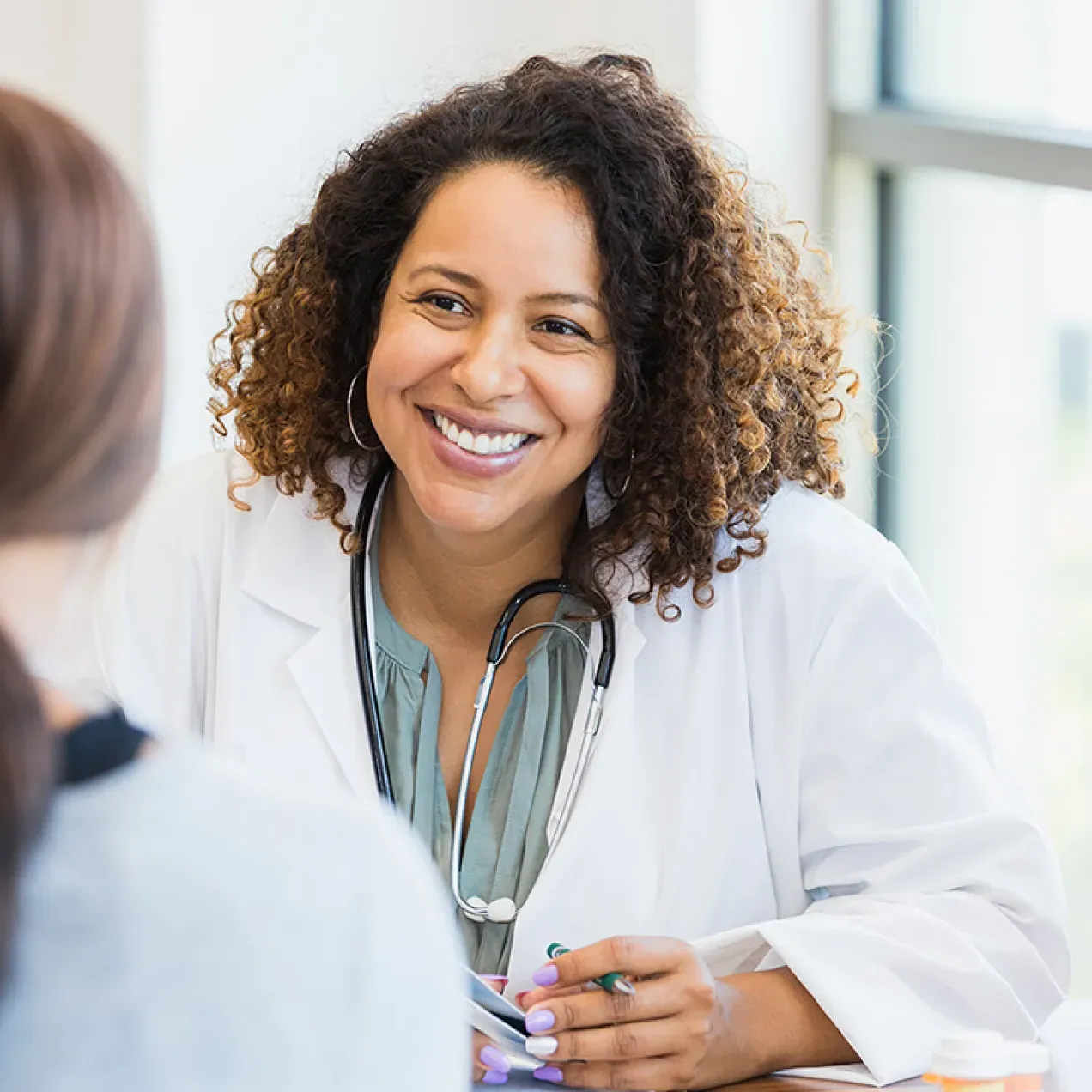 Women's health nurse practitioner smiling while speaking with female patient